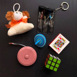Example trinkets from this batch, a plush dog, a mini screwdriver keychain, a spinning top, playing cards and a tape measure