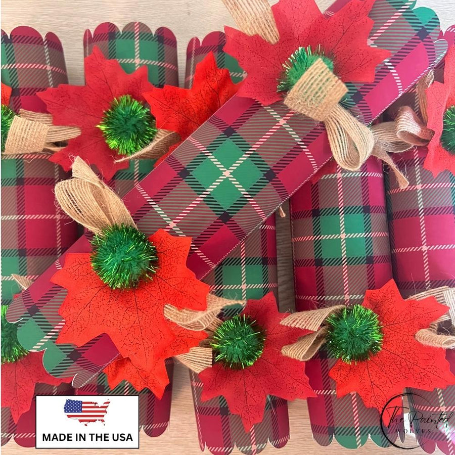 Six red and green plaid Christmas crackers tied with burlap bows, red leaves and green pom poms