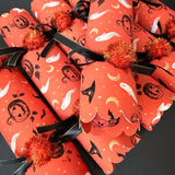 Information card listing what is inside each Halloween cracker: a novelty gift, a paper hat, an extra toy, a joke and a snap