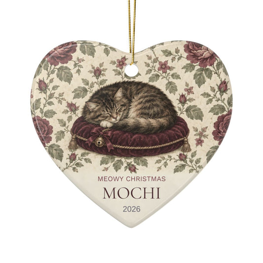 Personalized cat heart ornament, Meowy Christmas with a sleeping tabby on a velvet cushion, sample name Mochi, 2026
