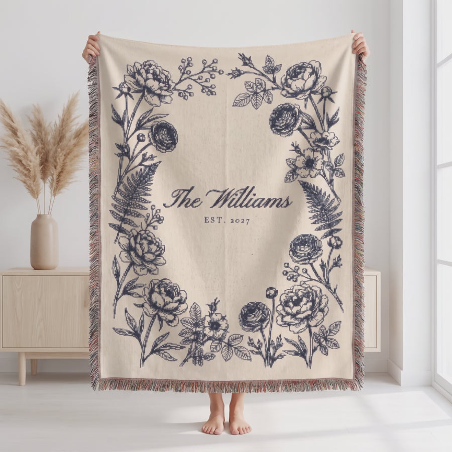 Personalized family name woven blanket in navy, held up, fabric moving