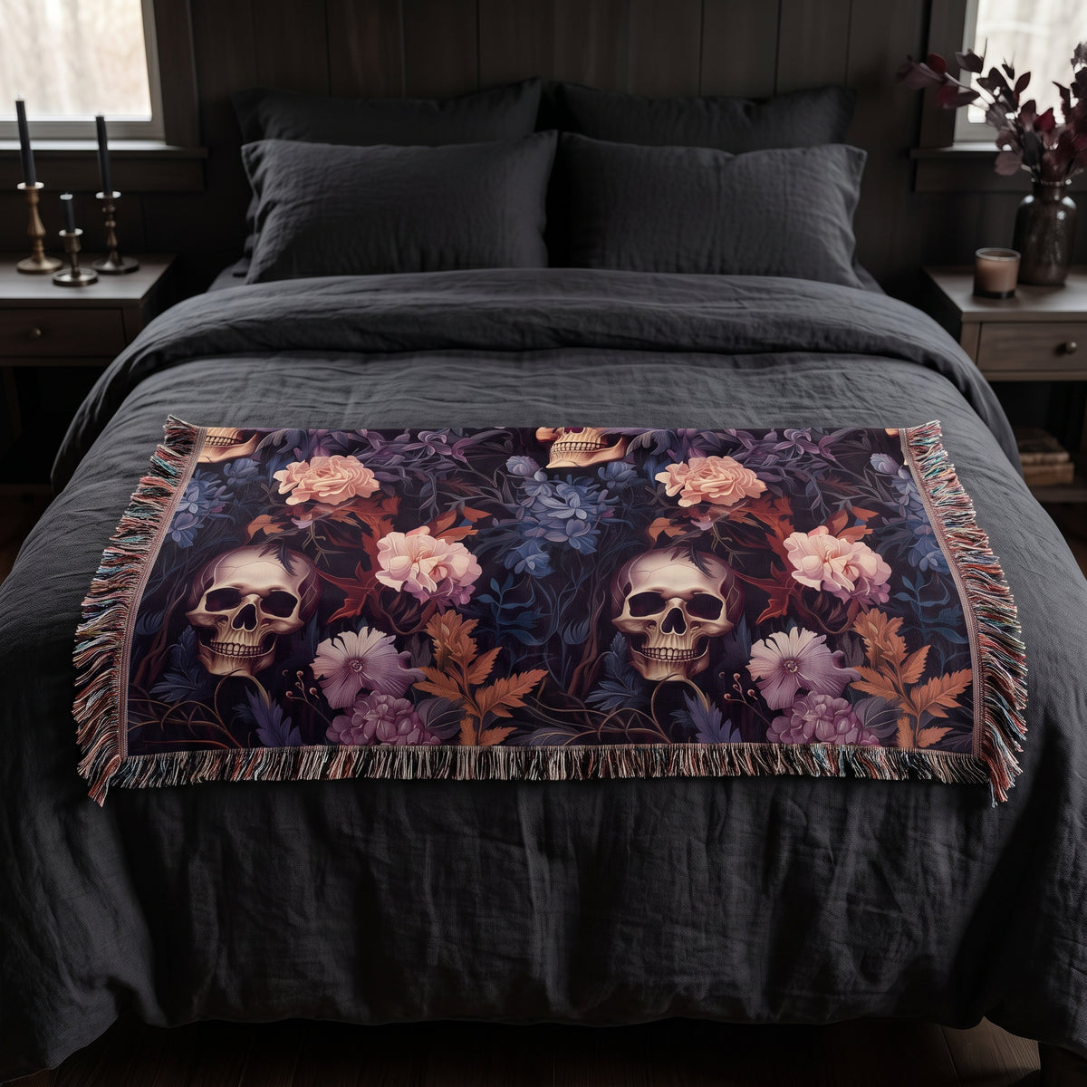 Questionably Cute skull and flowers woven blanket folded across the foot of a queen bed with charcoal linen
