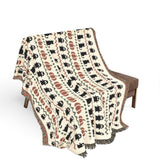 Haunted Heirloom woven blanket draped over a chair, showing the ghost and black cat pattern
