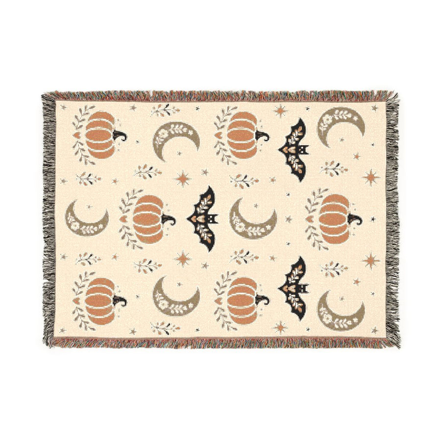 Subtle Spooky neutral Halloween woven blanket laid flat, cream weave with orange pumpkins, tan moons and black bats, multicolor fringe