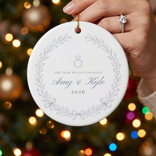 Hand with engagement ring holding the blue wreath engagement ornament